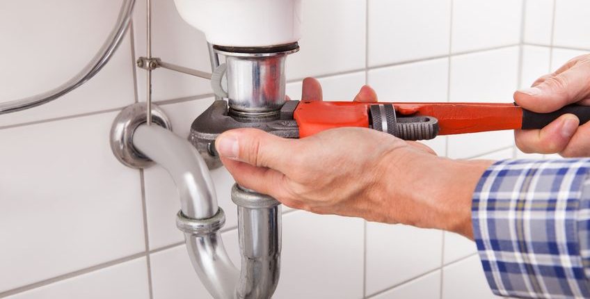 close-up of male plumber fitting sink pipe in bathroom