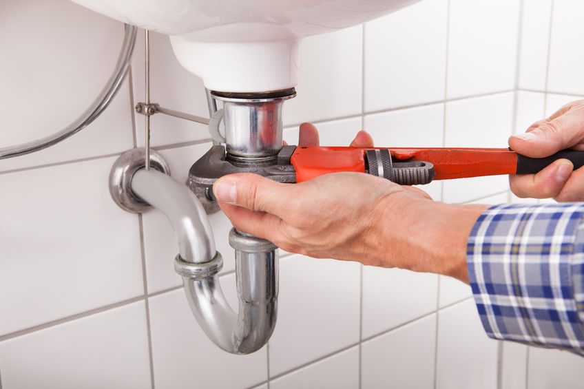 close-up of male plumber fitting sink pipe in bathroom