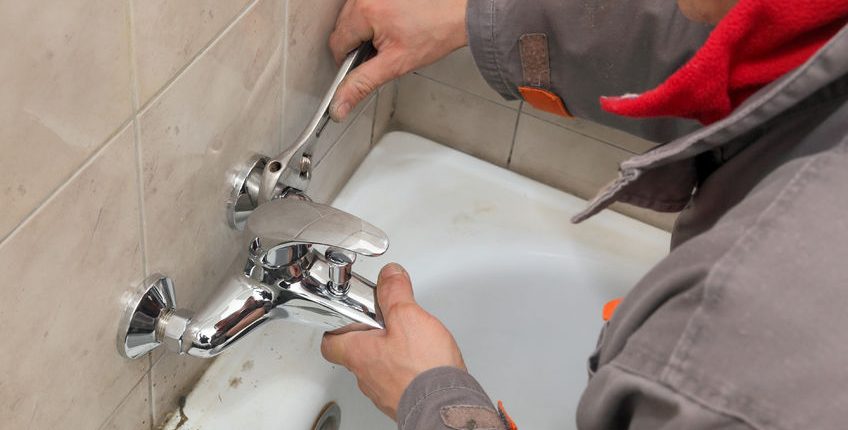 plumber fixing water tap in a bathroom using spanner