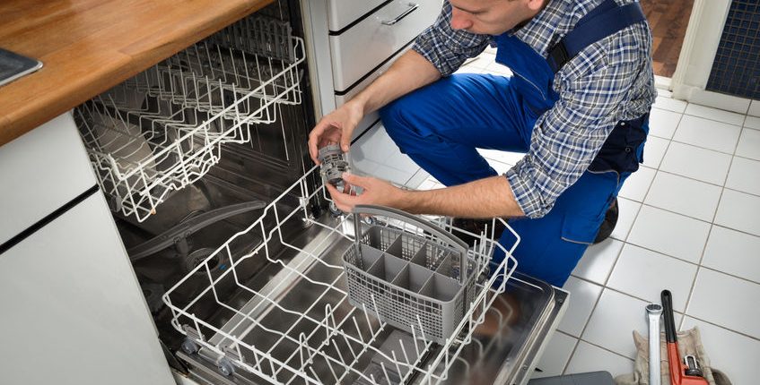 portrait of male technician repairing dishwasher in kitchen