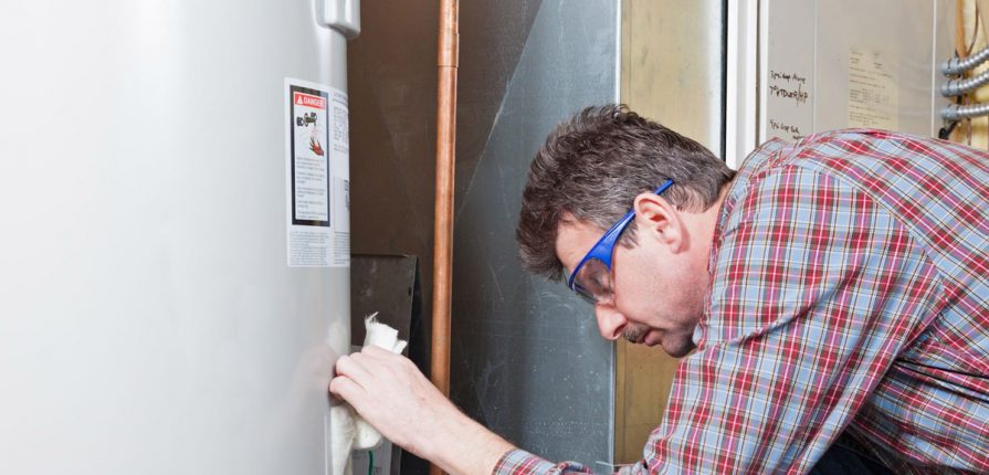 Male plumber fixing a water heater